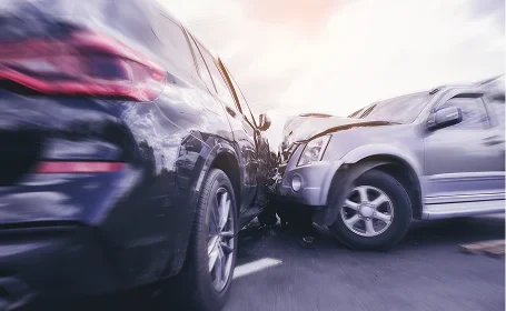 A close-up of a severe collision between a black SUV and a silver vehicle, with visible damage and crumpled metal
