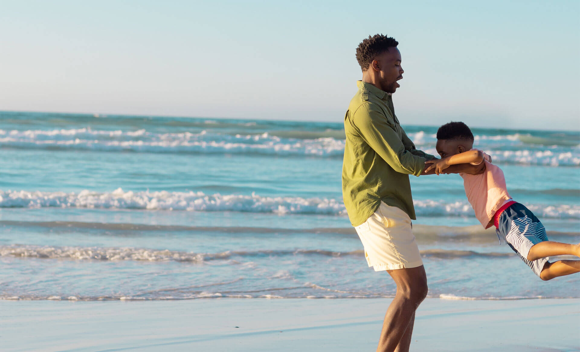 African American father and son playing on beach