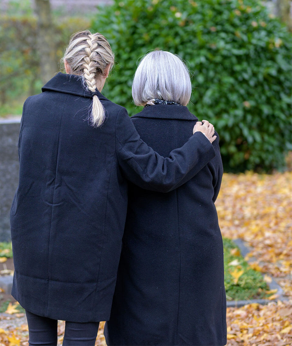 Younger woman with arm around older woman.