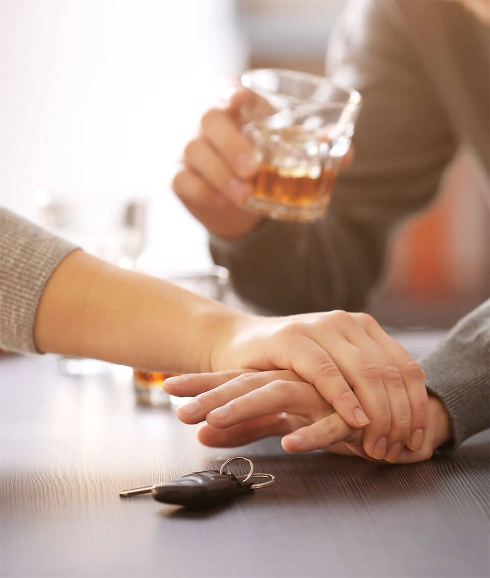 Person with alcoholic beverage in hand reaching for car keys