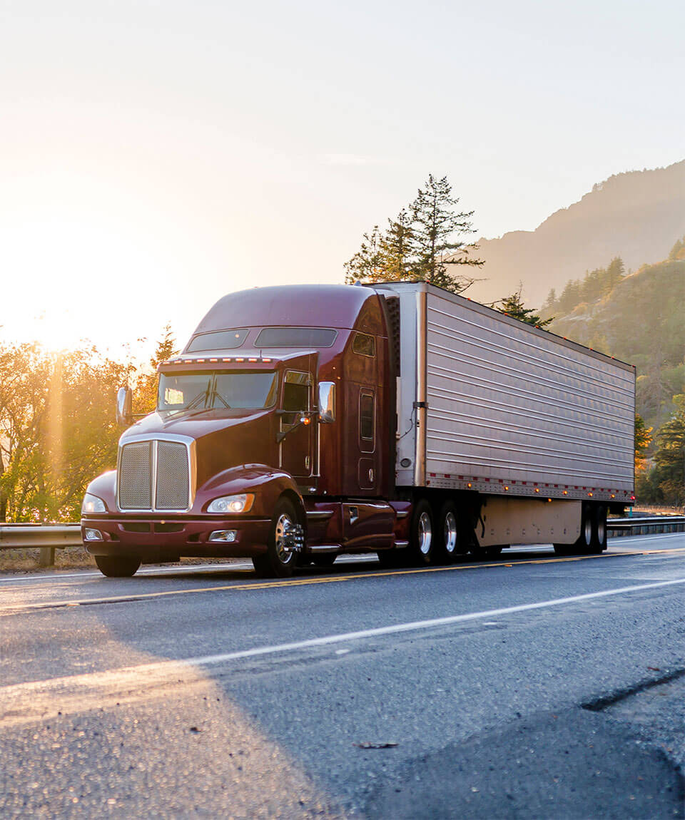 Semi truck on road with mountains in the background.