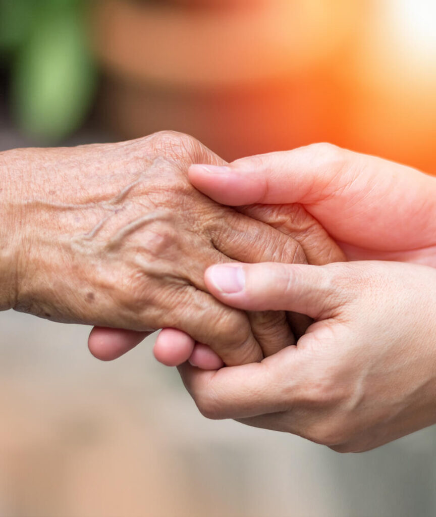 Young person's hand holding senior's hand.