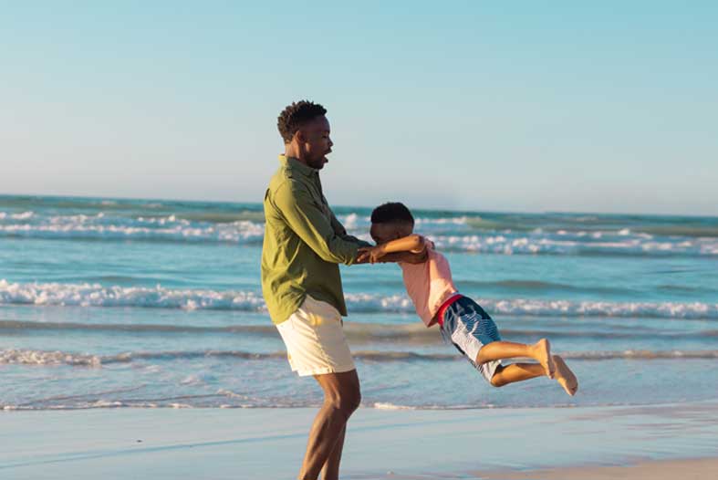 African American father and son playing on beach